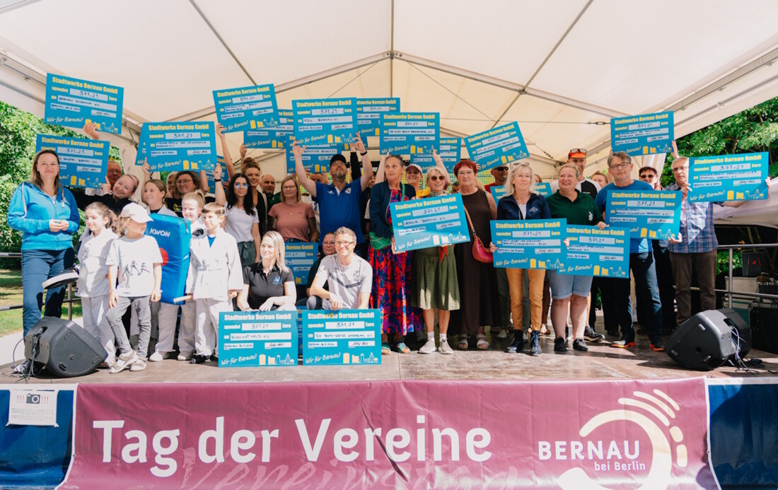 Viele Menschen stehen auf der Bühne vom Tag der Vereine und halten jeweils einen Spendenscheck hoch.