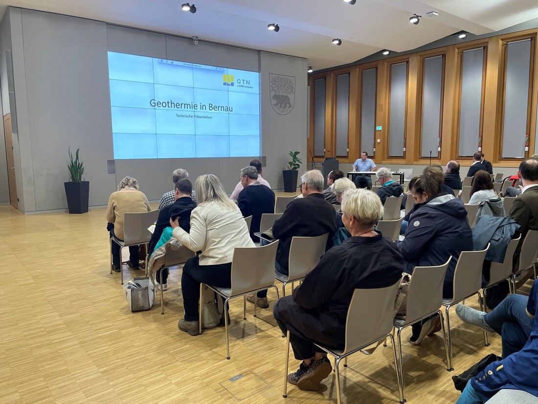 Besuchende der Geothermieinfoveranstaltung sitzen auf Stühlen und schauen auf eine Power-Point-Präsentation.