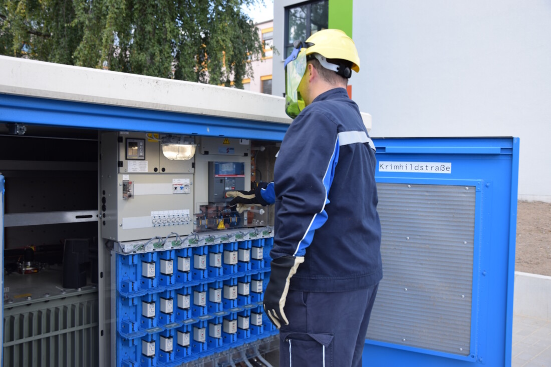 Stromnetzmonteur schaltet an der Trafostation eine Leitung um. Er trägt die passende Schutzausrüstung. 